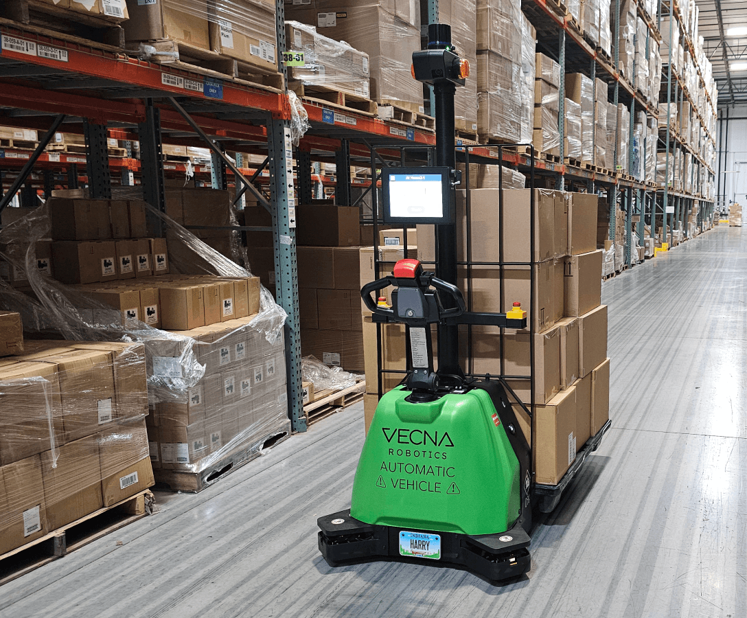 Autonomous pallet jack transporting boxed pallets through a warehouse aisle