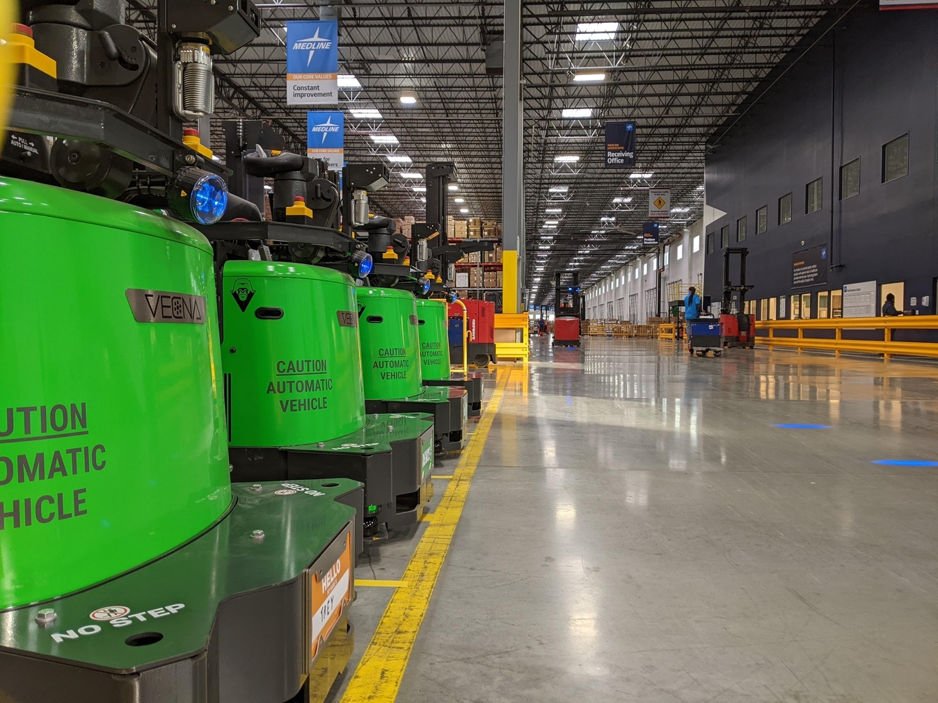 Row of autonomous vehicles staged along a warehouse safety line